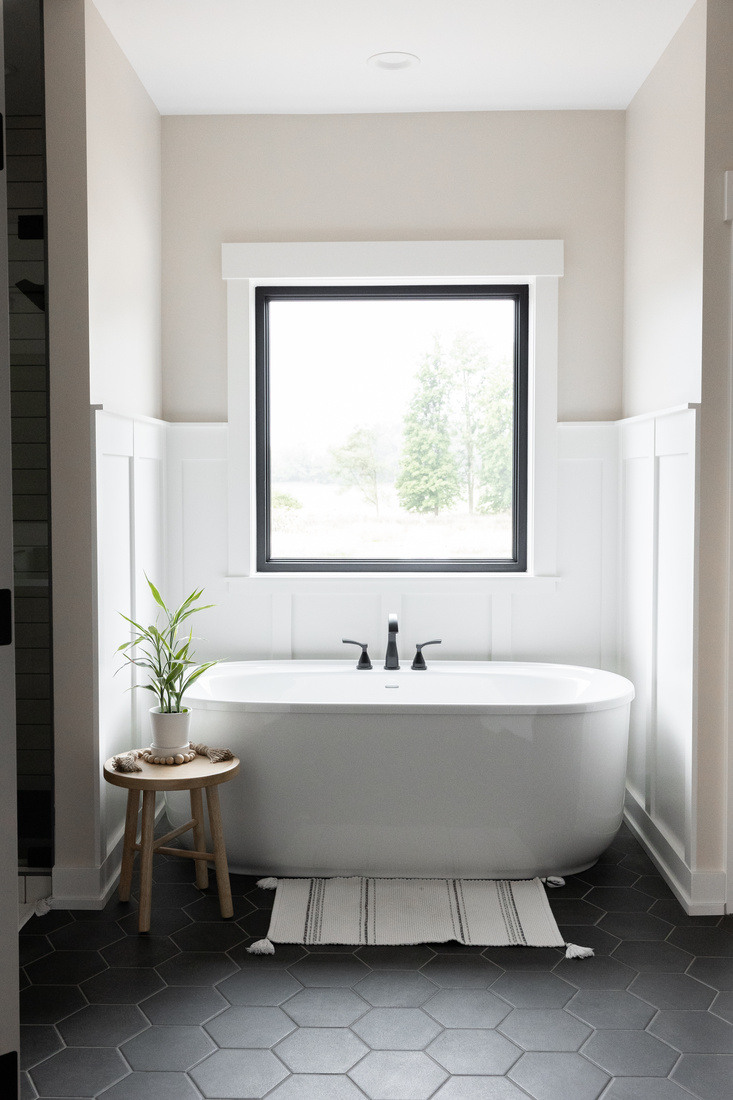 Soaking tub with window view and dark hex tile in a West Michigan main floor remodel by Ridgewood Home Construction