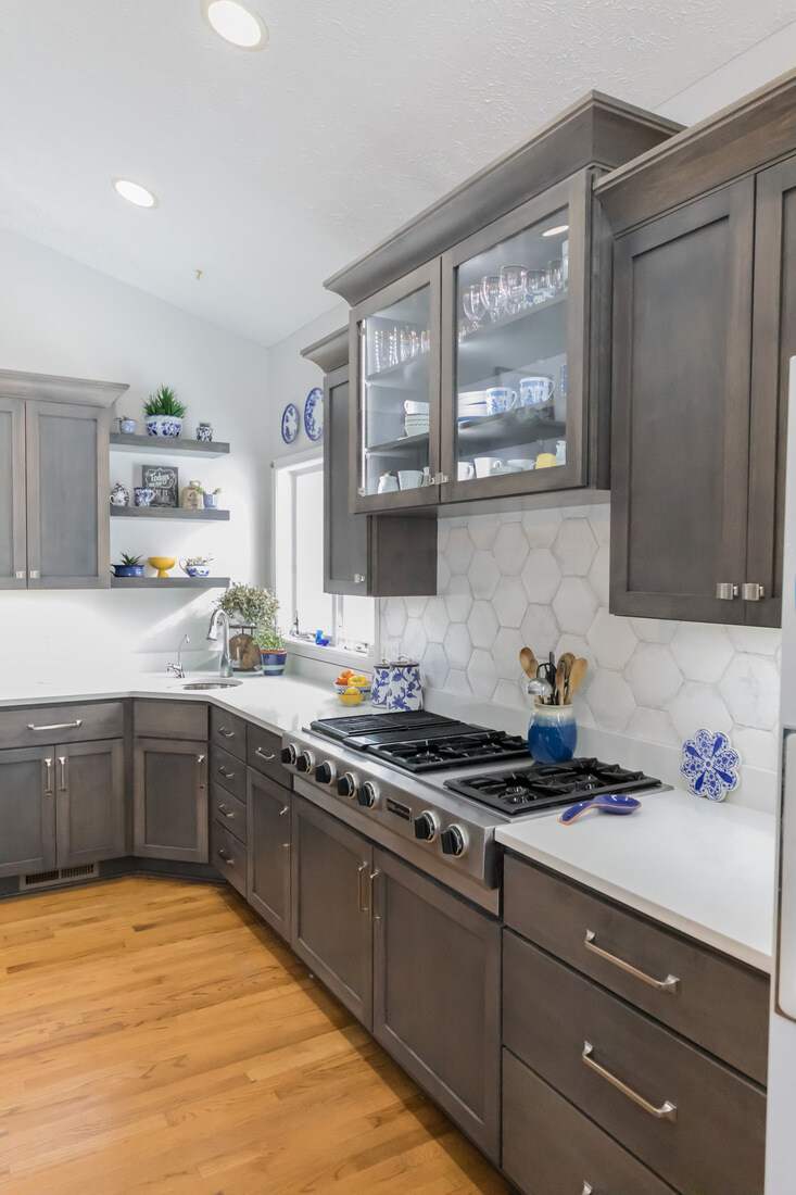Cooktop area with large hex tile backsplash and glass-front cabinets in Cascade kitchen remodel by Ridgewood Home Construction