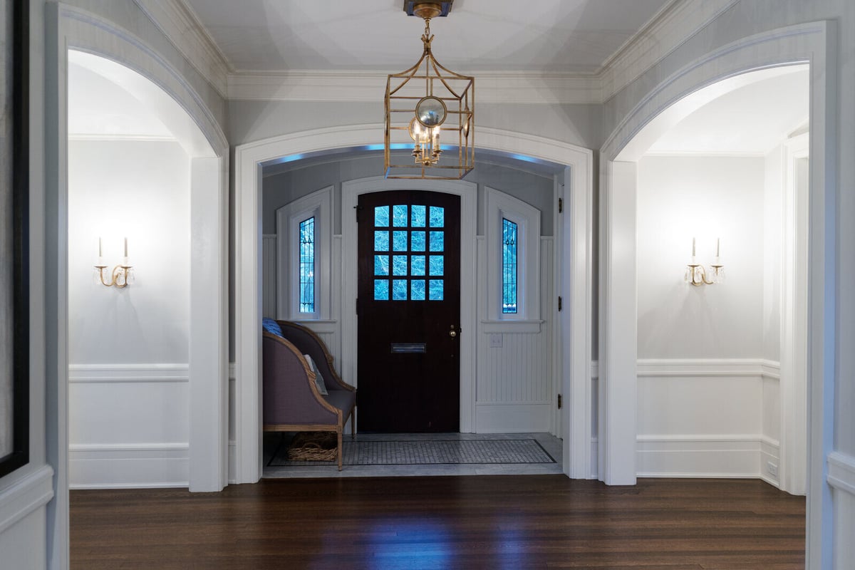 Entryway renovation with arched openings and dark wood front door by Ridgewood Home Construction in East Grand Rapids