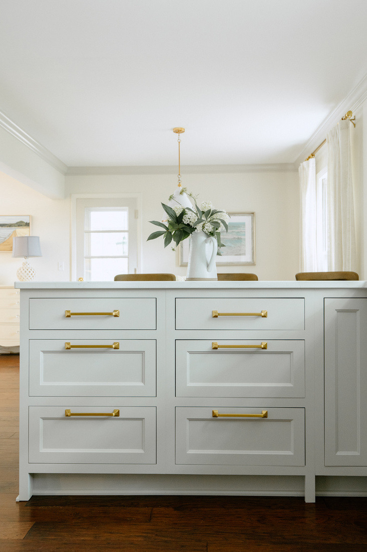 Custom kitchen island with gold hardware and flower arrangement in East Grand Rapids remodel by Ridgewood Home Construction