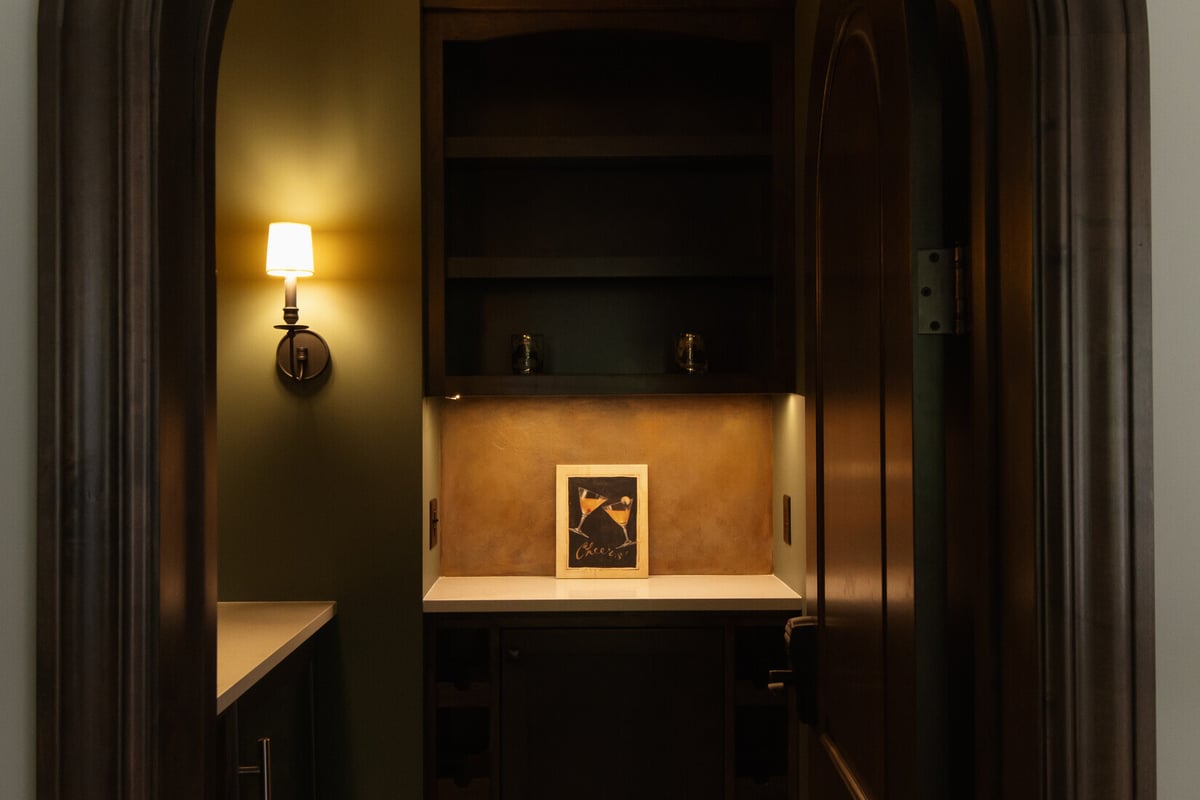Basement bar nook with warm lighting and “Cheers” wall art by Ridgewood Home Construction in Grand Rapids Township