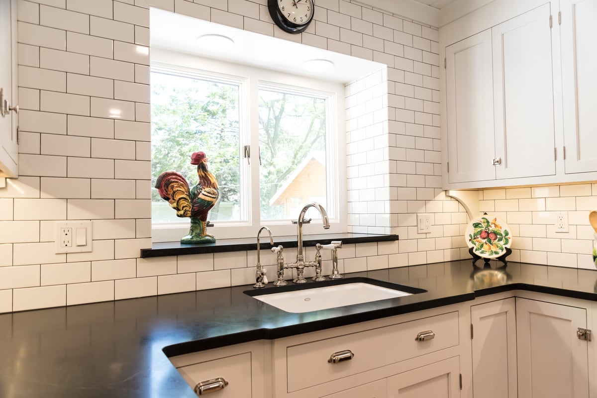 Kitchen sink under bright window with rooster statue in Ridgewood Home Construction remodel in Rockford, MI