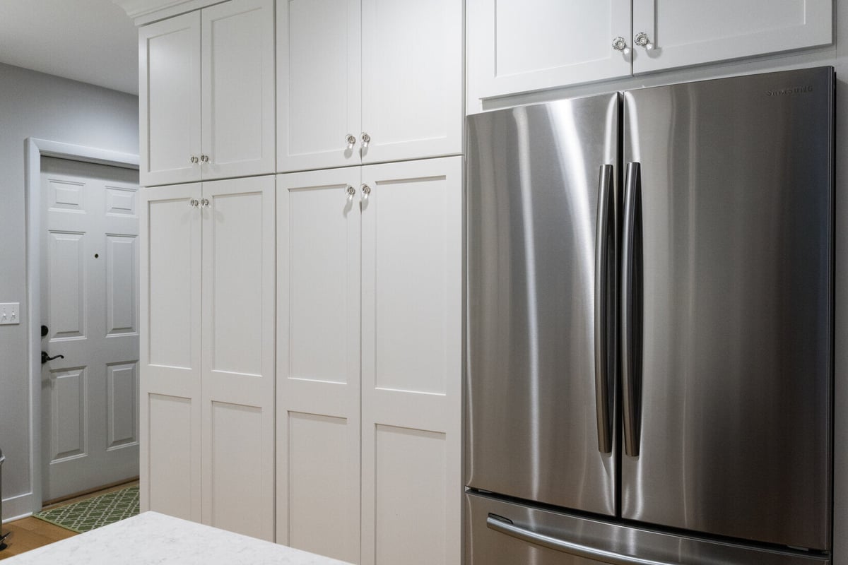 Floor-to-ceiling white cabinetry with stainless steel fridge in Rockford kitchen remodel by Ridgewood Home Construction