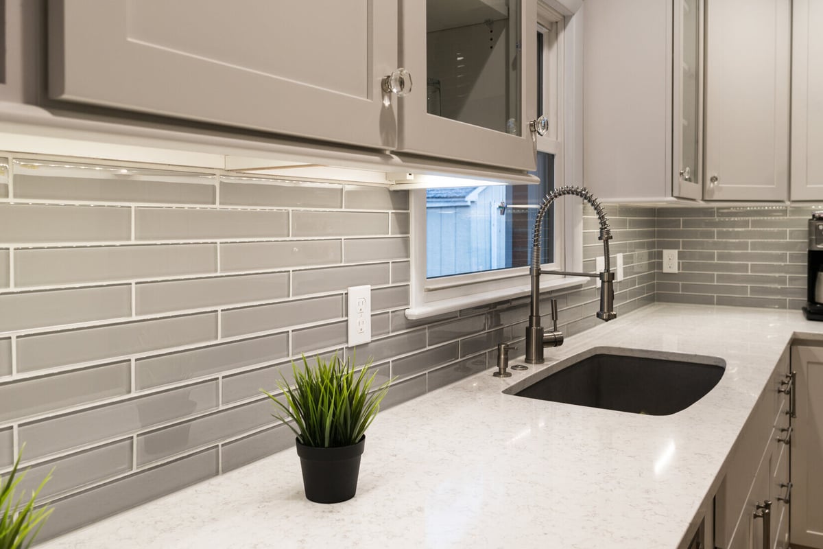 Modern kitchen remodel in Rockford, MI by Ridgewood Home Construction featuring gray glass tile backsplash and under-cabinet lighting