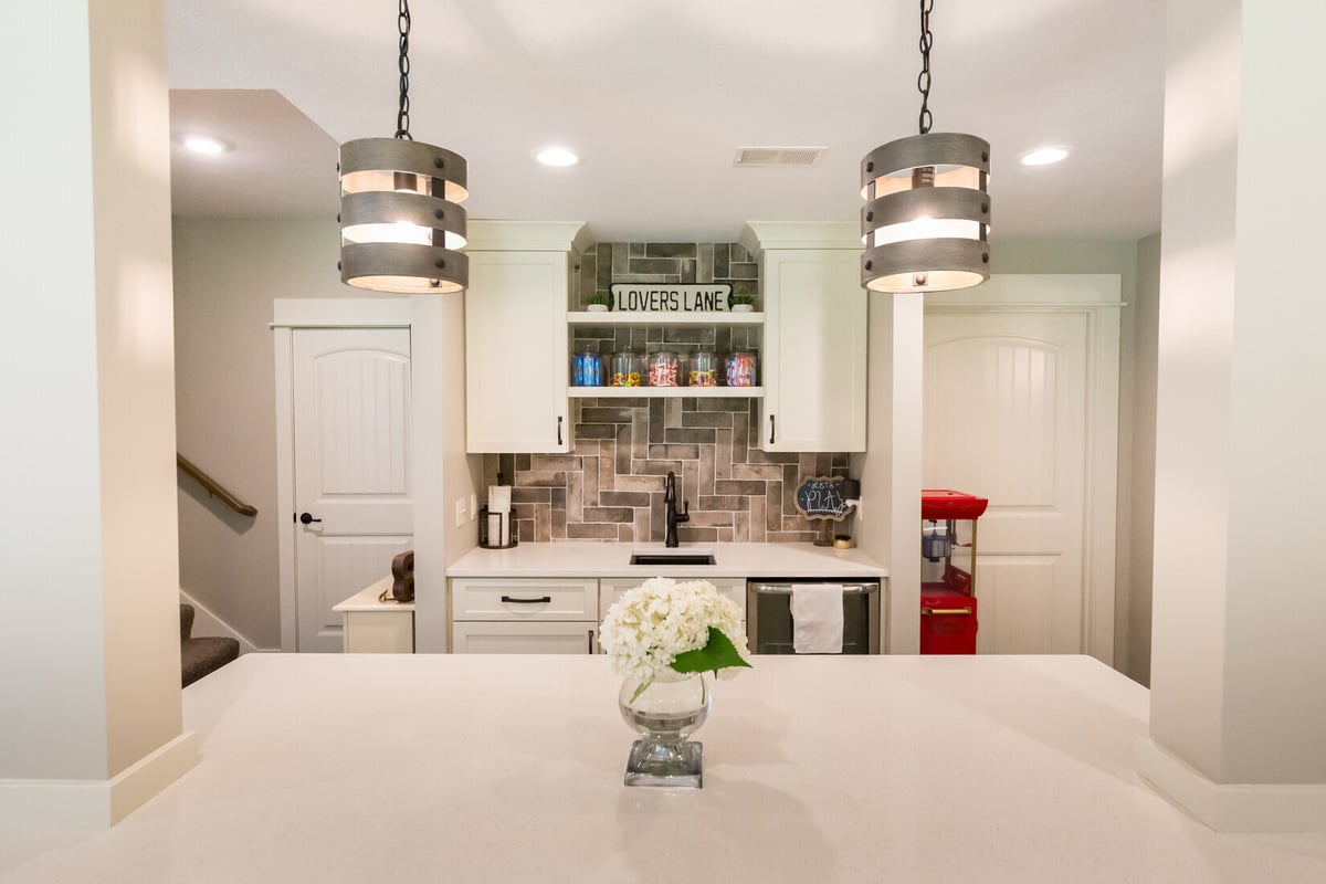 Basement kitchen and bar area in Sparta, MI featuring pendant lights and custom cabinetry by Ridgewood Home Construction